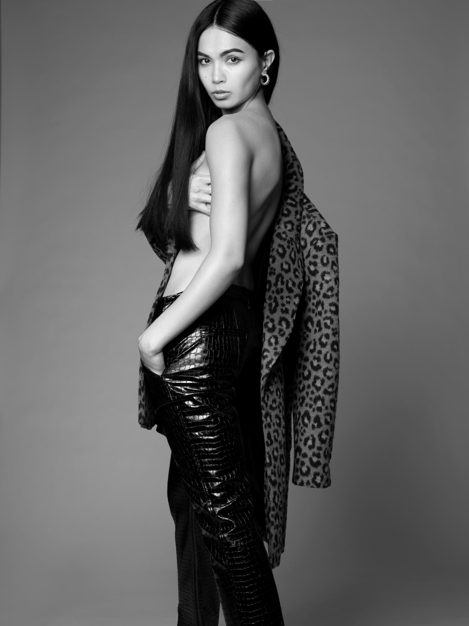 Black-and-white portrait of Shirin Hojayeva in a leopard coat draped off her shoulders, looking back with a sultry gaze.