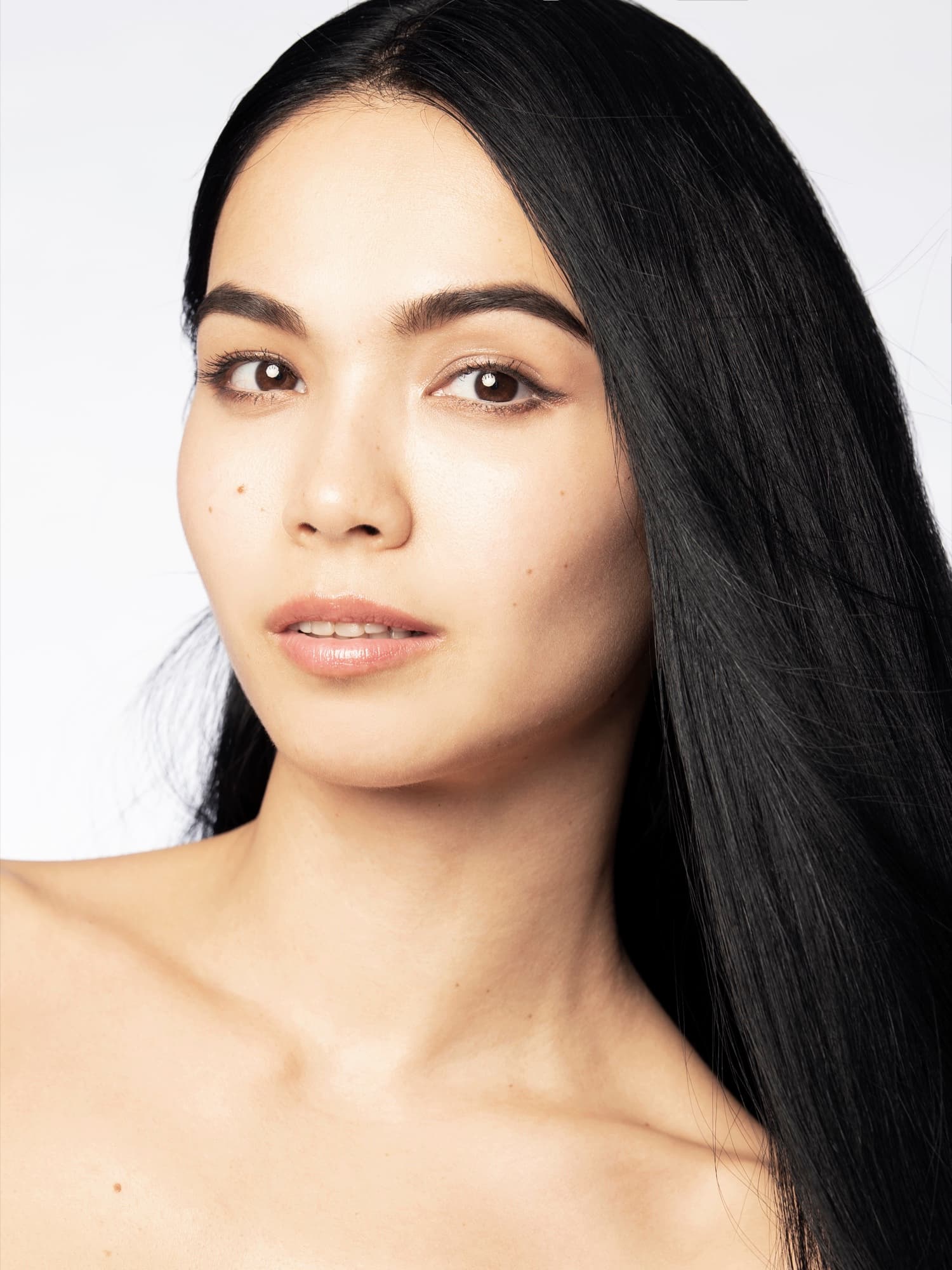 Shirin Hojayeva gazes softly off-camera in a clean beauty close-up with natural makeup against a white backdrop.