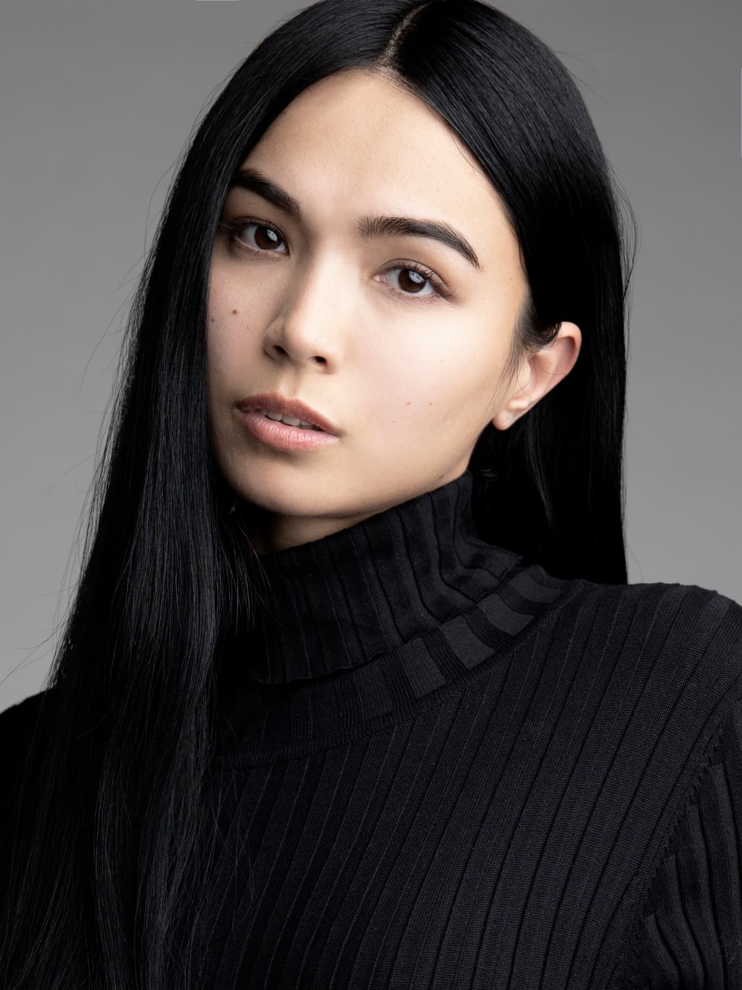 Headshot of Shirin Hojayeva in a black ribbed turtleneck with straight hair framing her face, looking contemplative.