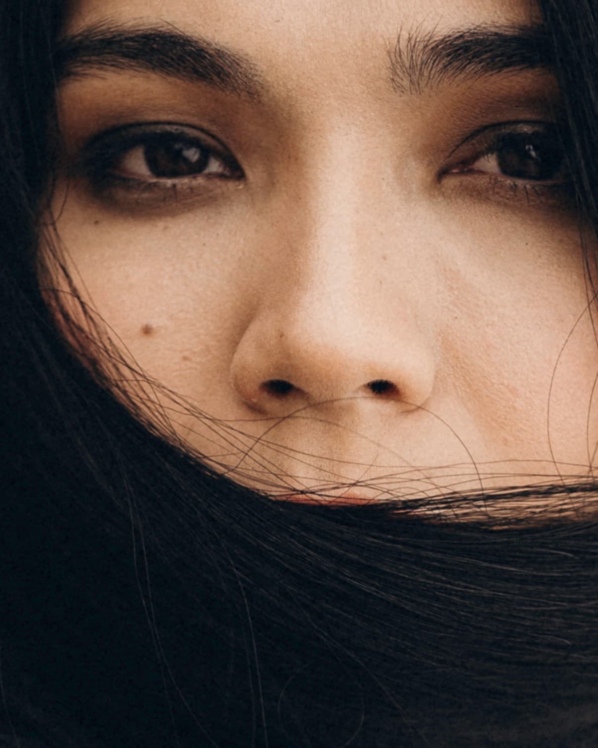 Extreme close-up of Shirin Hojayeva with windblown hair across her face, capturing an intimate and mysterious mood.
