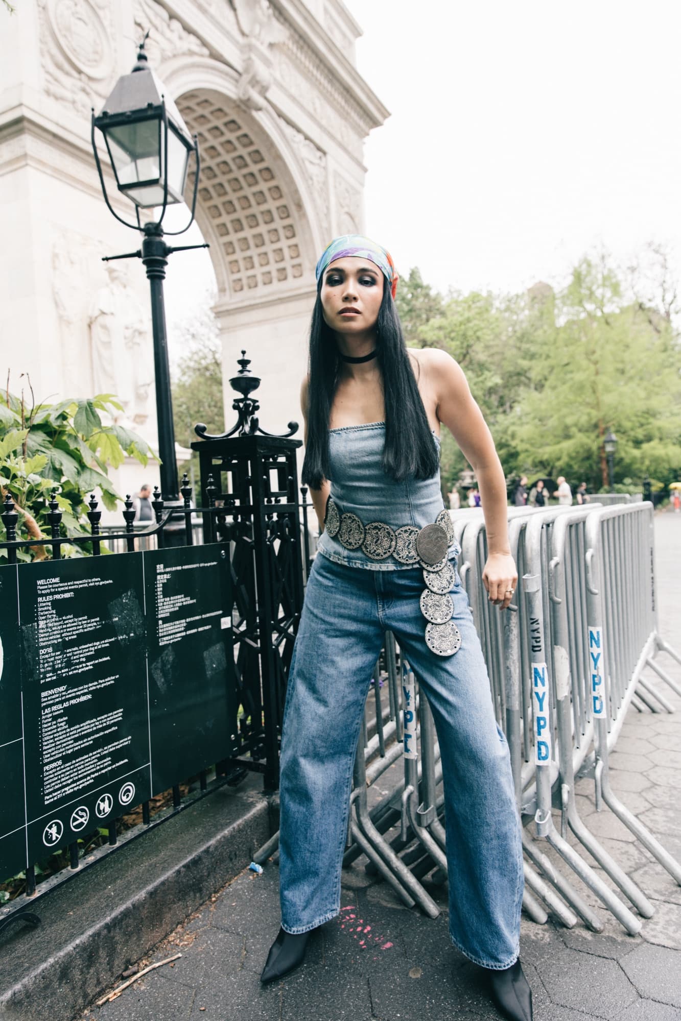 Shirin Hojayeva stands by Washington Square Arch in wide-leg jeans, a denim corset top, and a colorful headscarf.