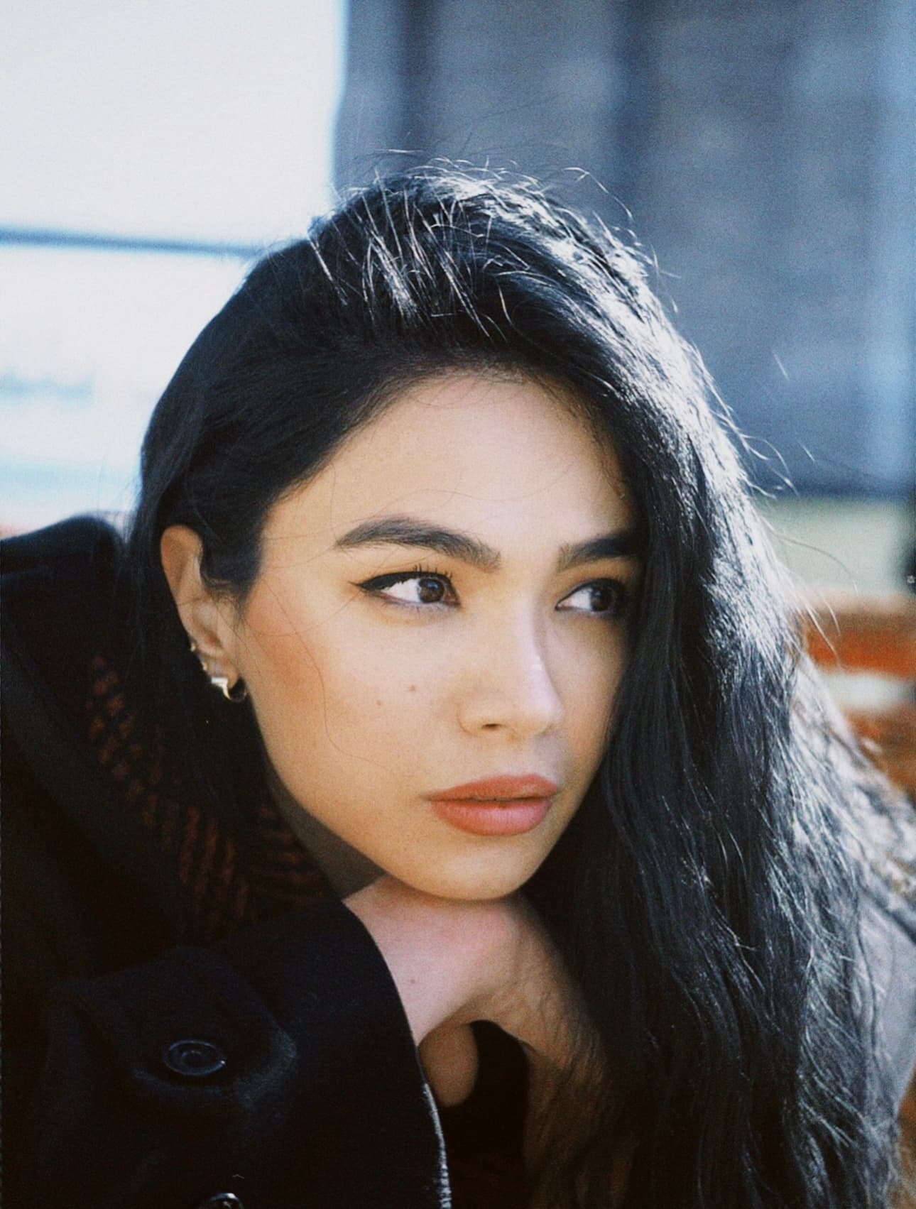Intimate close-up of Shirin with tousled dark hair and gold hoop earring, shot on film with a wistful expression.