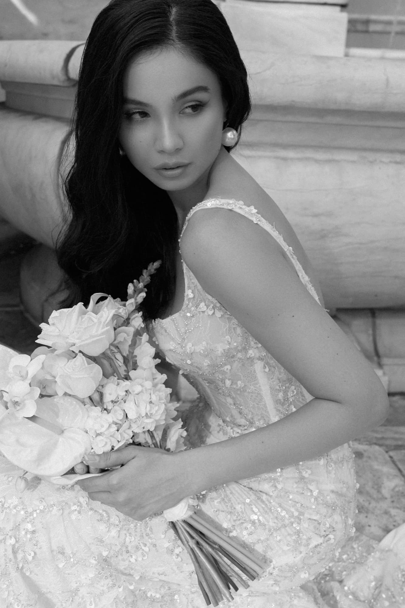 Black-and-white close-up of Shirin seated in a beaded gown, cradling a bouquet and looking directly at the camera.