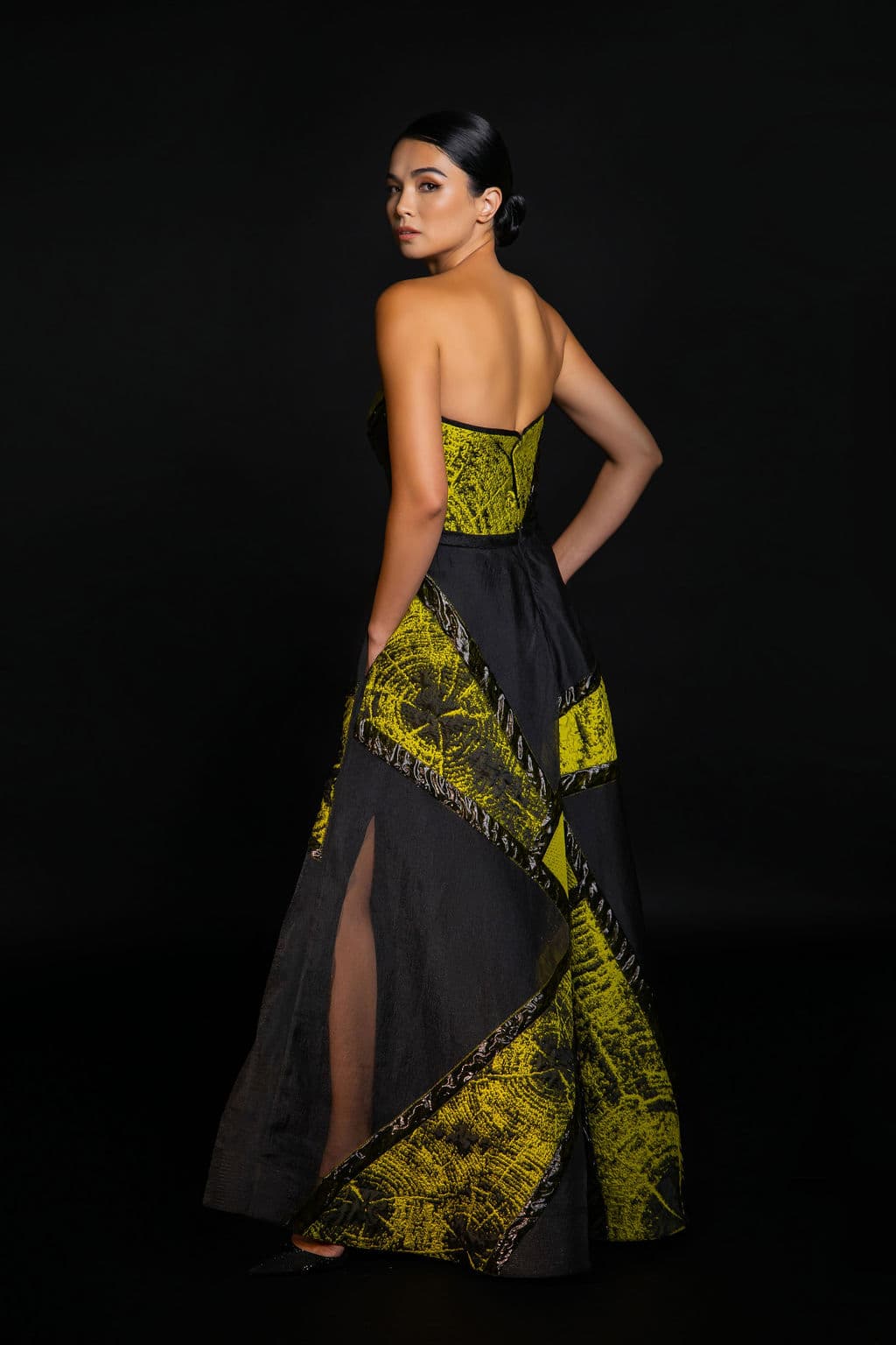 Shirin Hojayeva glances over her shoulder in a black and chartreuse strapless gown with a high slit, mood striking.